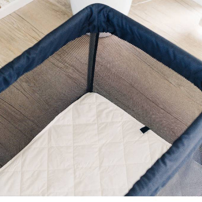 Quilted wool topper in a mesh travel cot