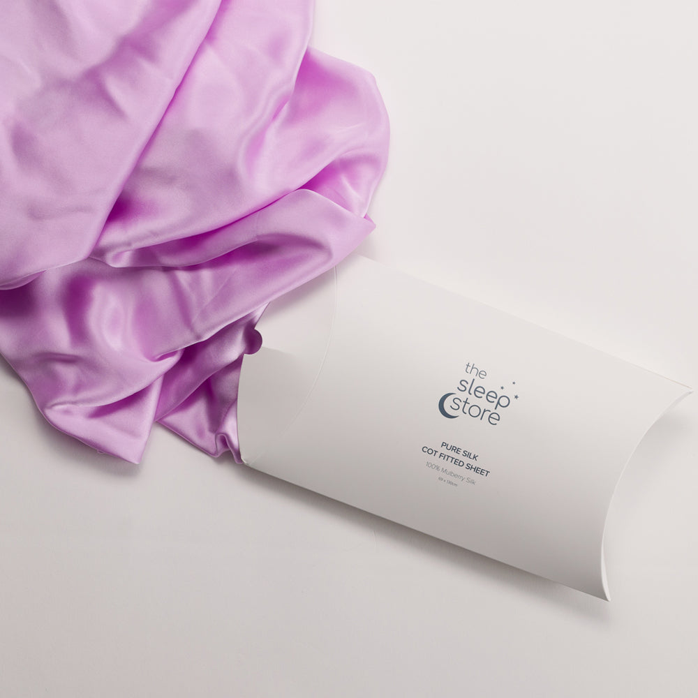 Purple satin fitted sheet on a white cylindrical packaging with 'The Sleep Store' branding.