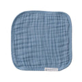 Blue muslin face cloth with brand label on a white background