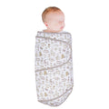 Newborn baby wrapped in a white forest patterned miracle blanket swaddle on a white background