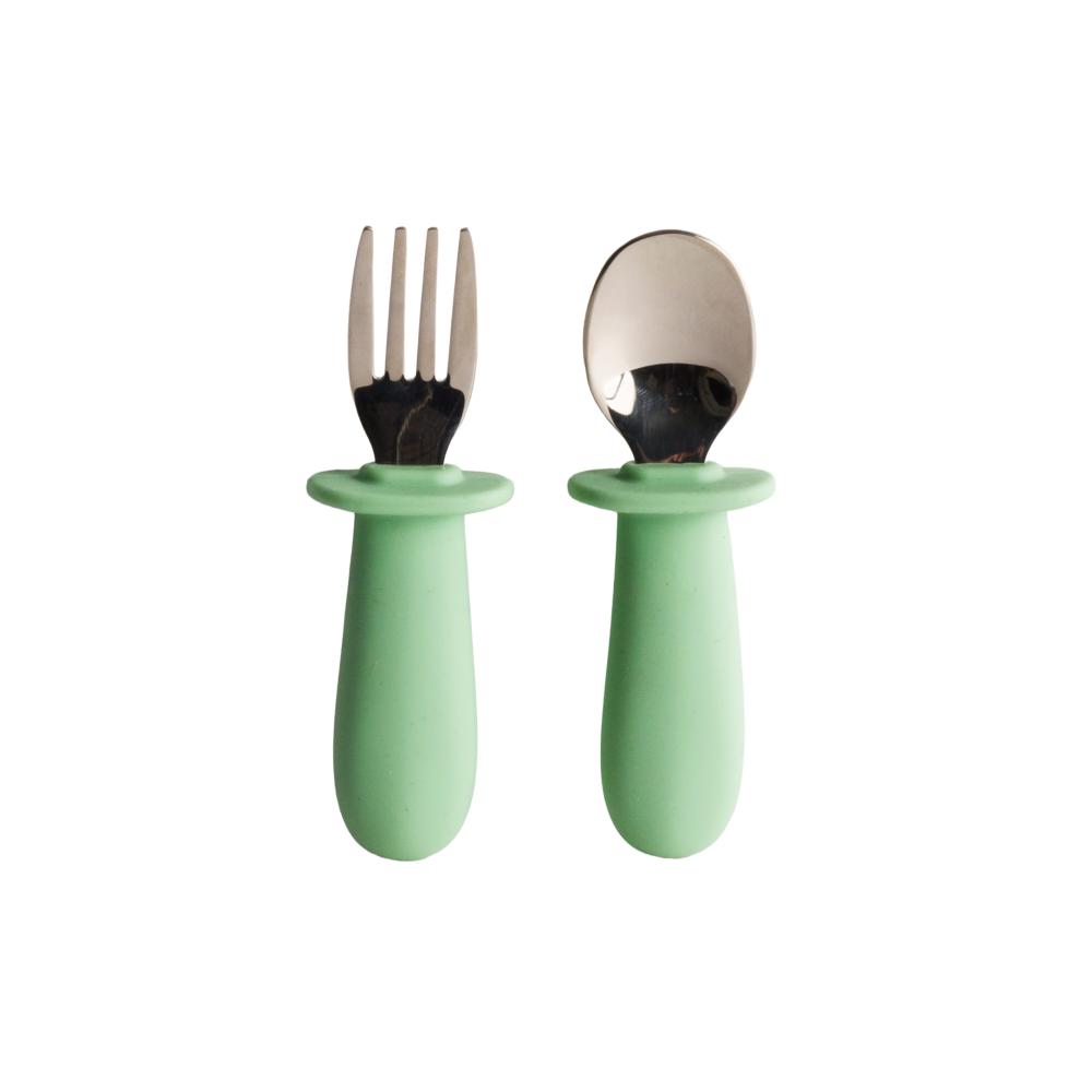 Set of stainless steel baby cutlery with green-handled fork and spoon on a white background