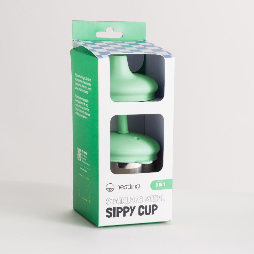 Green stainless steel sippy cup with silicone lids in a Nestling branded packaging box on a light gray background