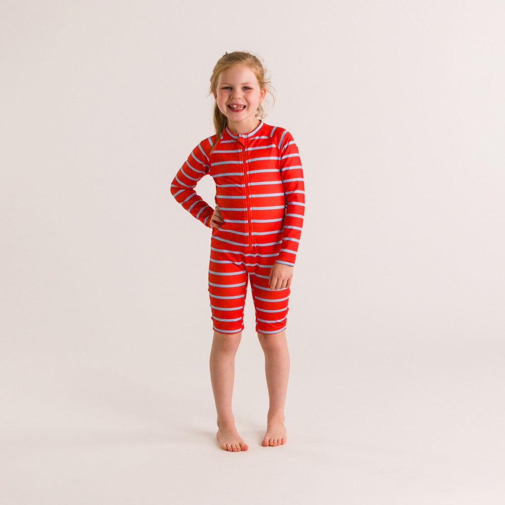 Child wearing a red striped swim suit on a plain background