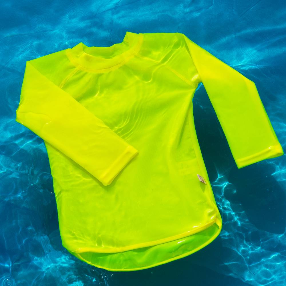 Neon yellow long-sleeve rash vest floating in clear blue water