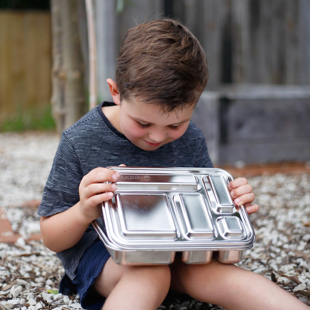 Child holding a metal lunch box outdoors