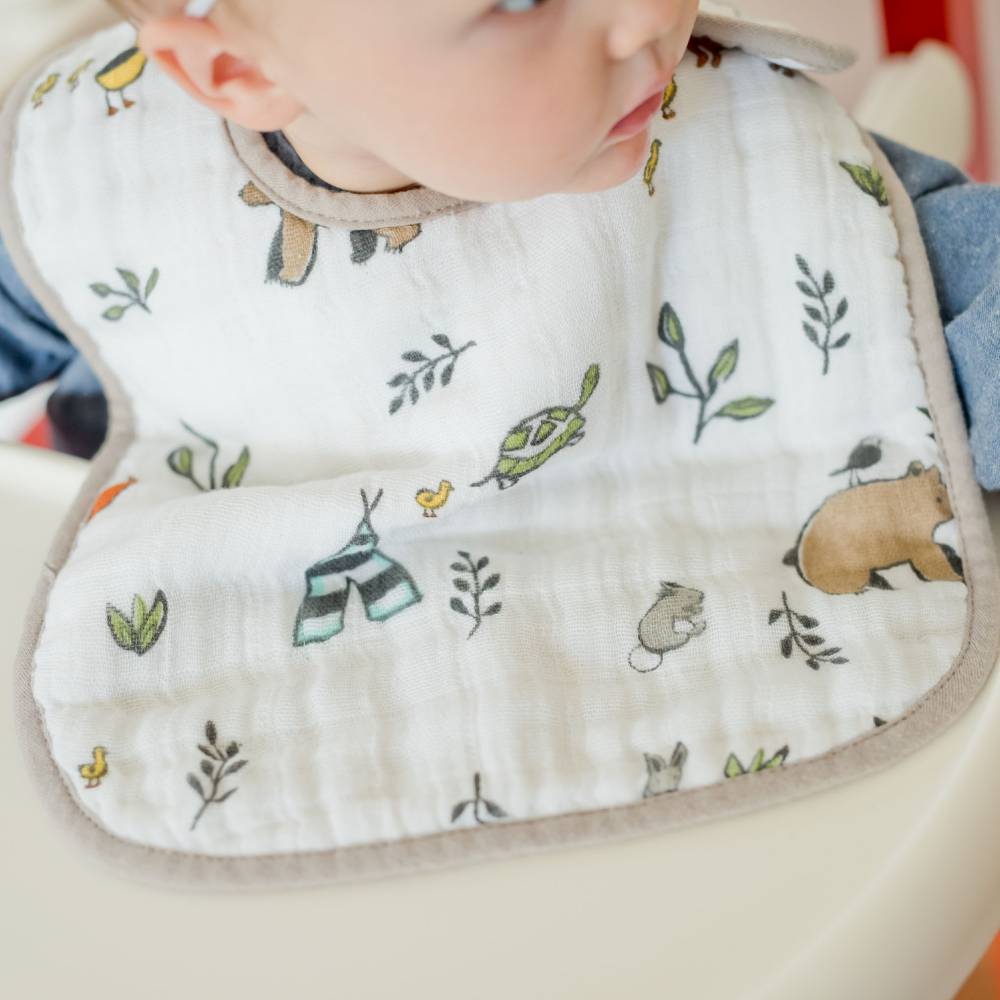 Close-up of baby wearing a white cotton muslin bib with nature-themed design