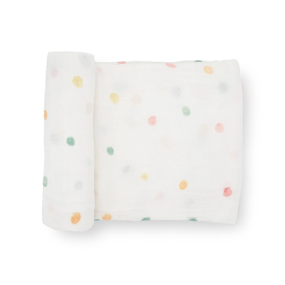 A white cotton muslin swaddle blanket with colourful dots patterns on a white background