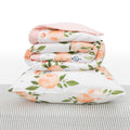 White Stackincluding baby blanket and pillow with watercolour rose patterns on a white background and grey striped sheet. 