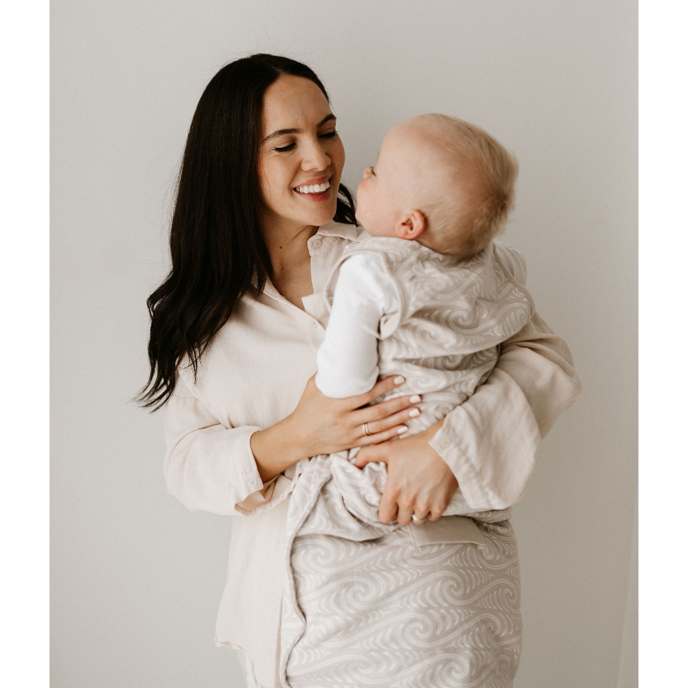 Woman holding a baby against a plain background