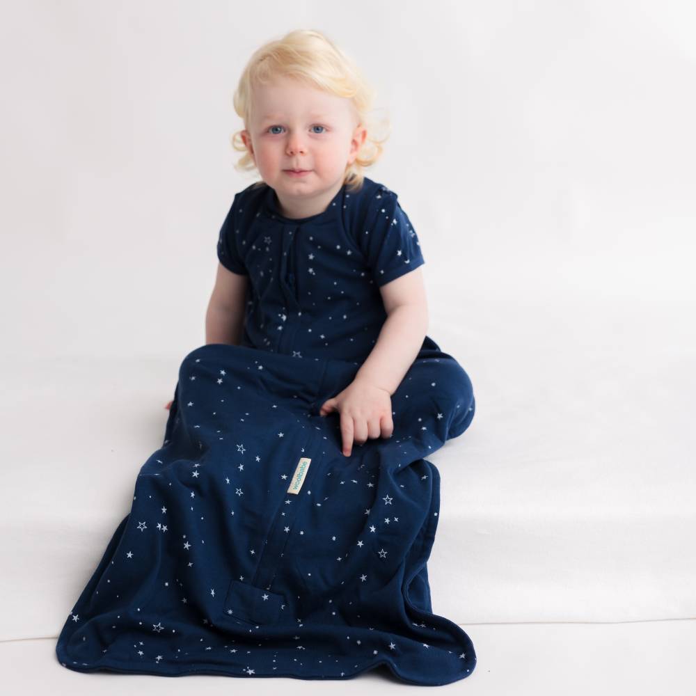 Child wearing a navy blue woolbabe toddler sleep sack with star patterns on a white background