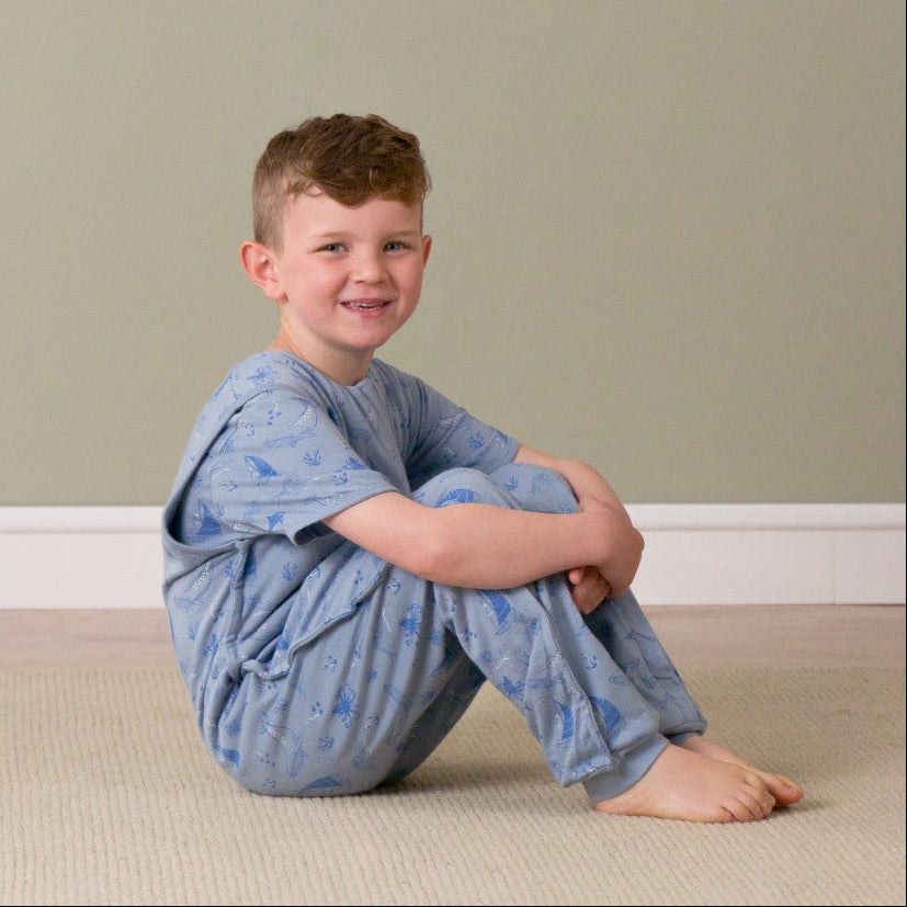 Child wearing a blue robe sitting on the floor against a plain wall.