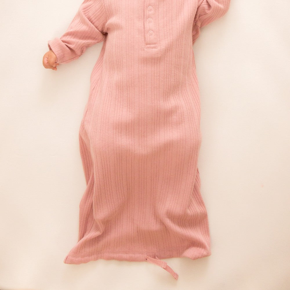 Pink merino baby gown with drawstring hem on a light beige background