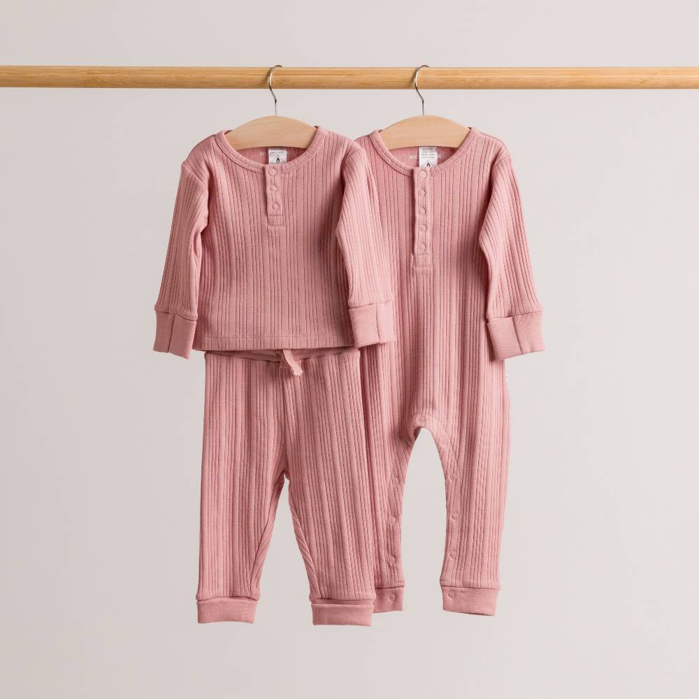 Pink woolbabe Daydream baby outfits set on hangers against a light gray background
