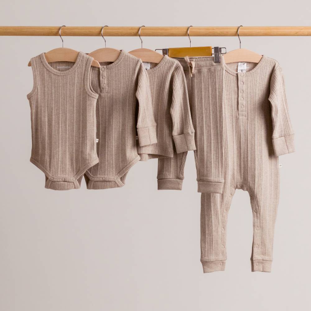 Dune marl collection of woolbabe baby clothing hanging on a rail