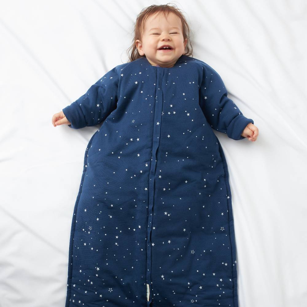 Child wearing a blue star-patterned sleeping bag on a white background