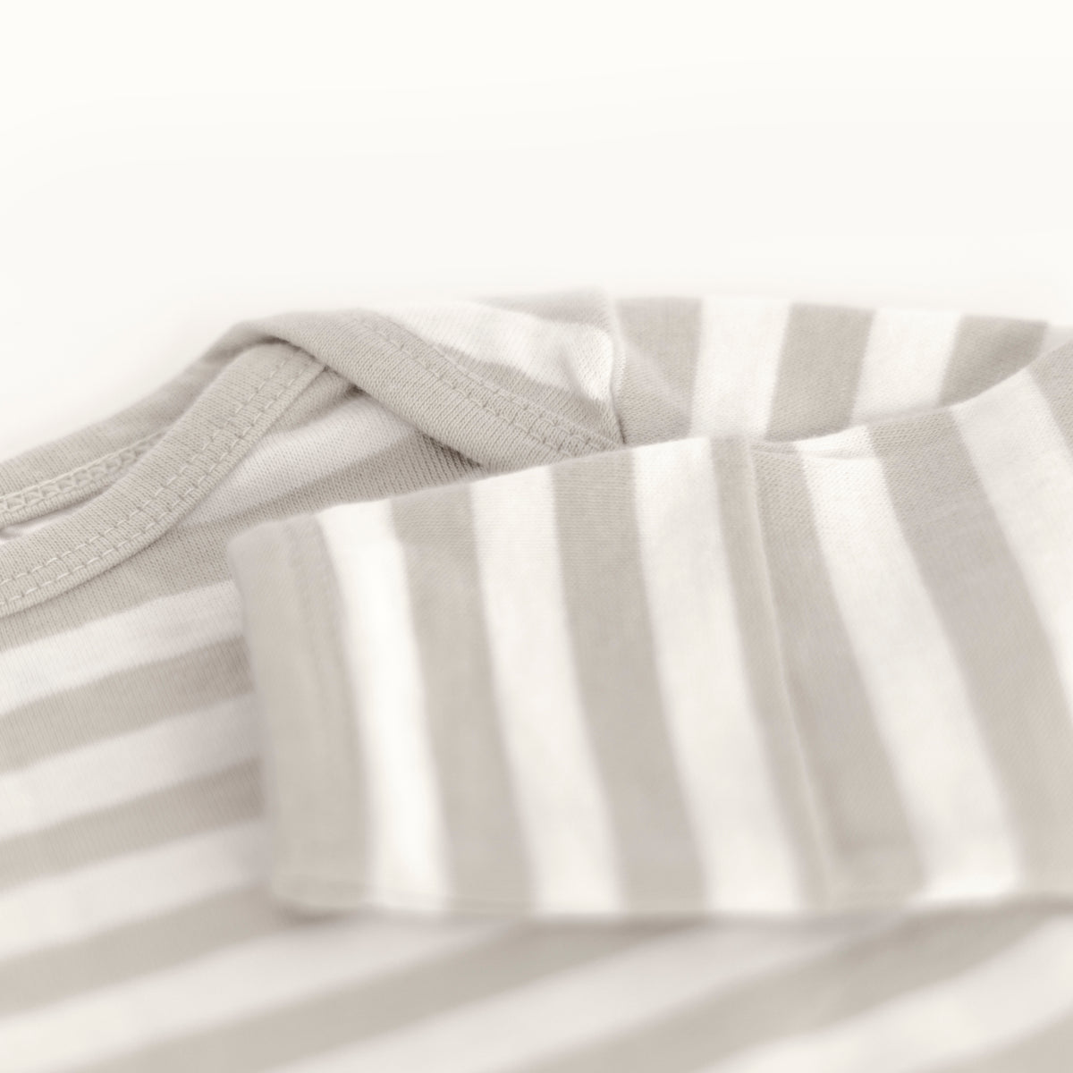 Close-up of the foldover baby mitten on a prem baby gown with horizontal grey stripes on a white background