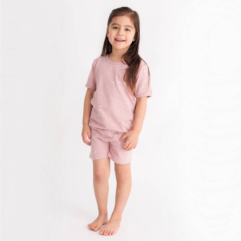 Young girl wearing a pink pajama set on a white background