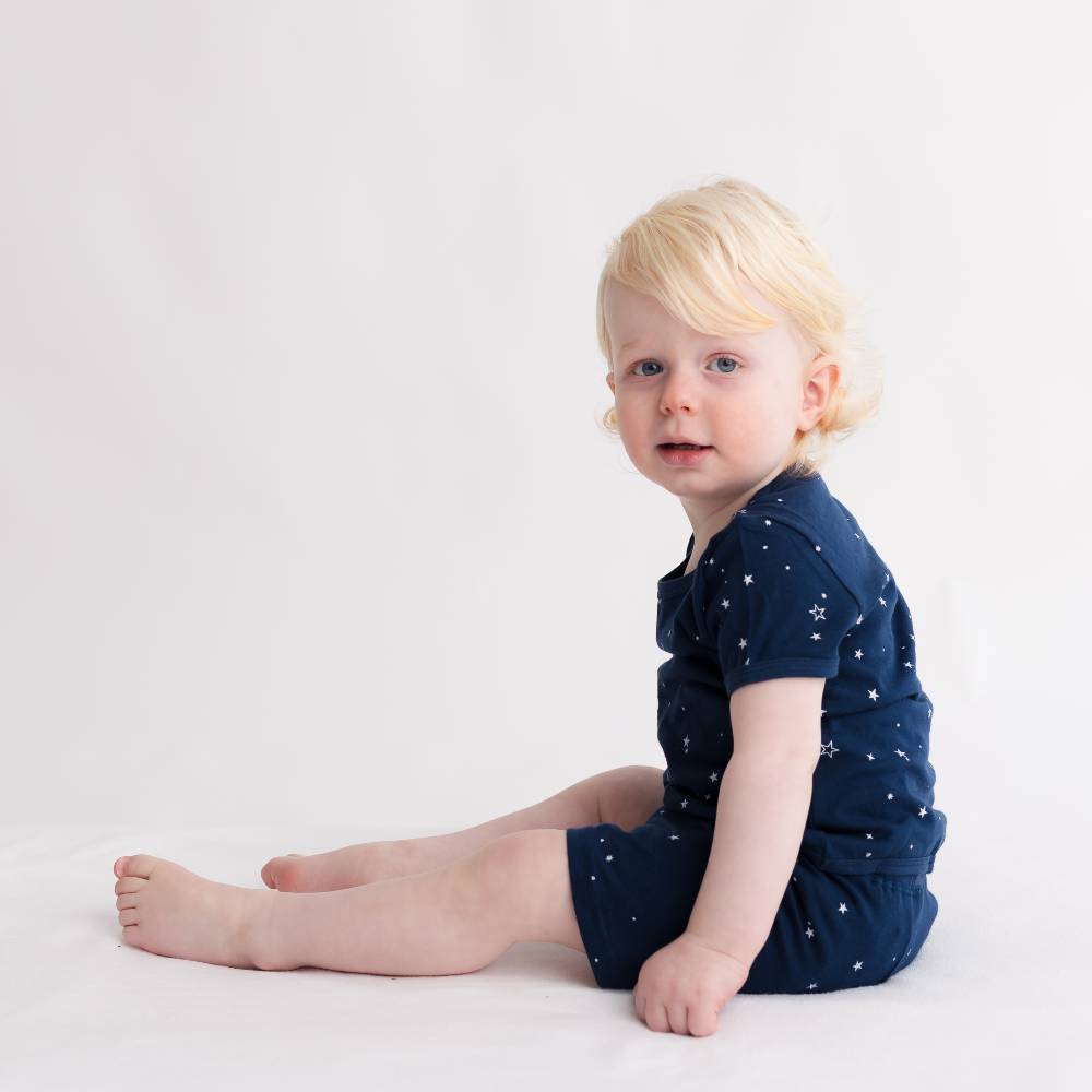 Child wearing a navy blue woolbabe PJswith white patterns on a light background