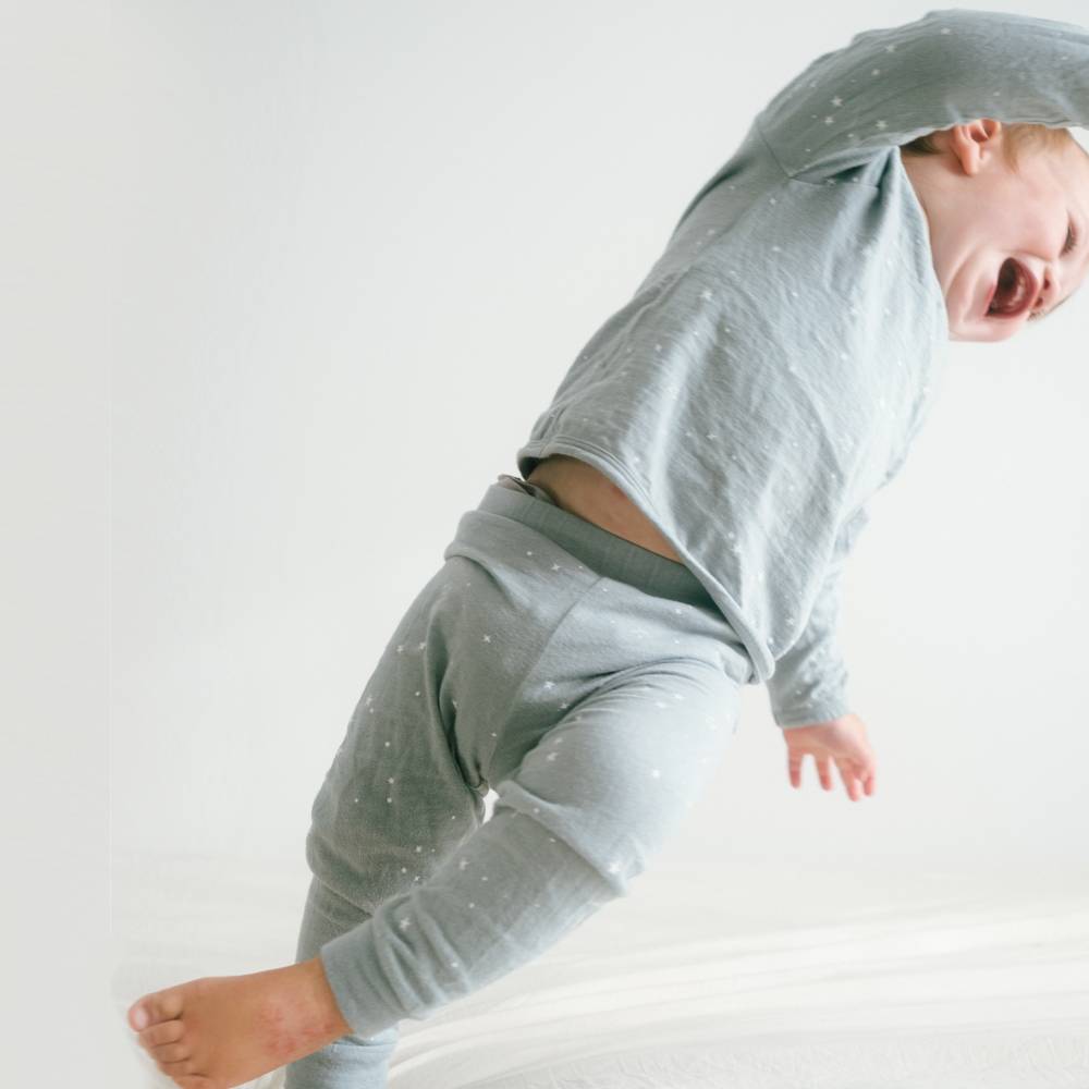Baby wearing a light gray outfit with a hood on a white background
