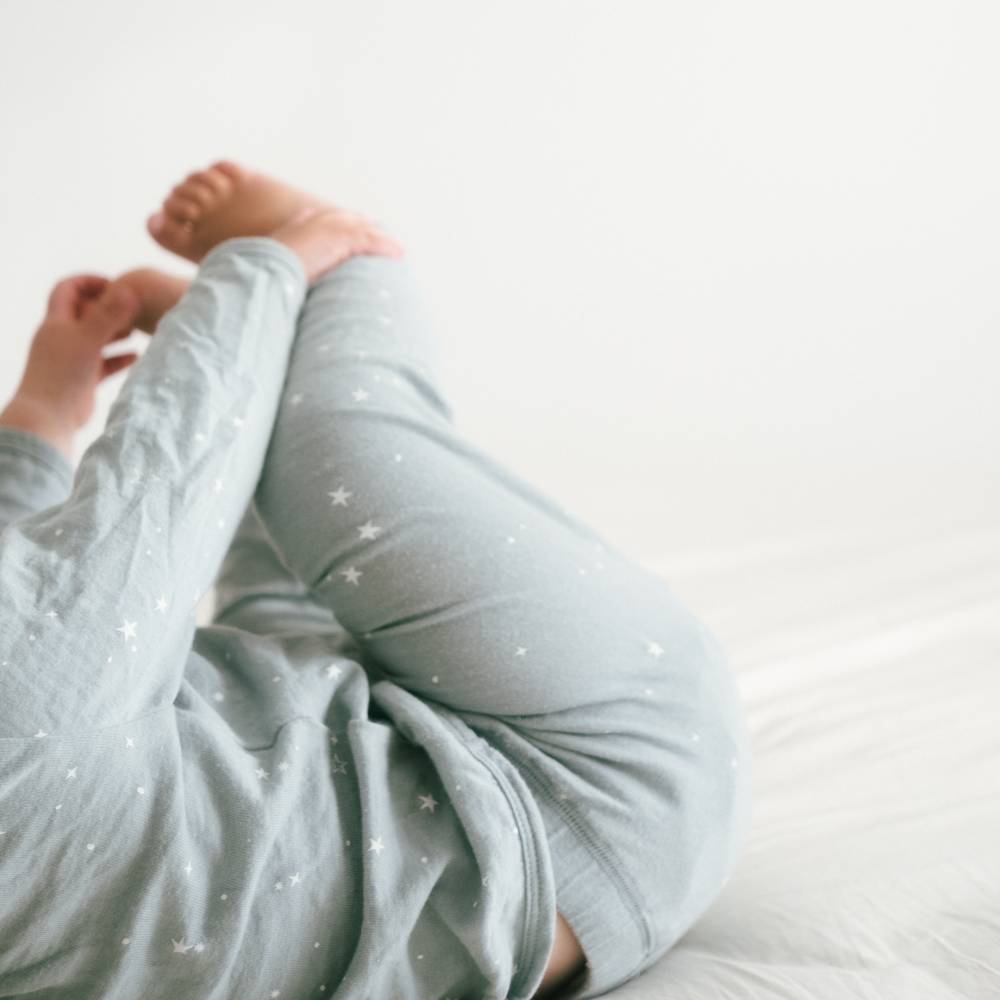 Person wearing light blue pajama pants with star patterns on a white background