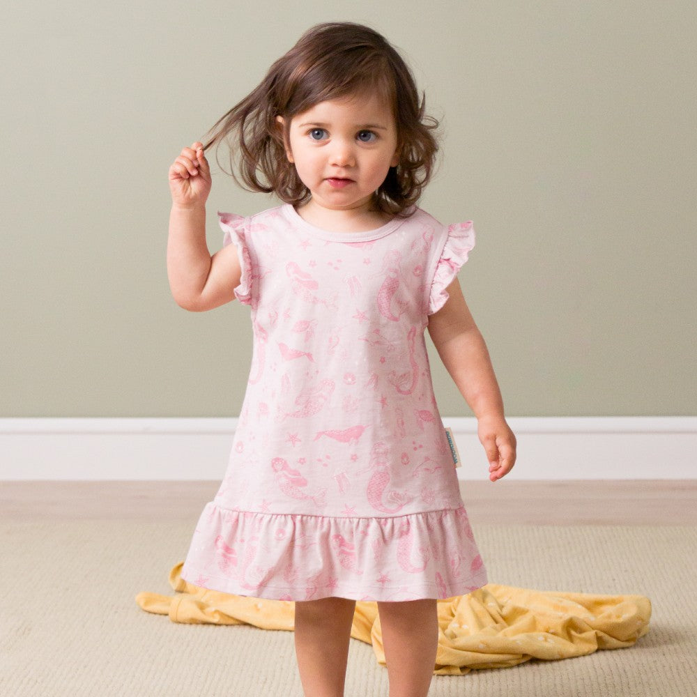 Young girl wearing a pink night dress with floral patterns on a neutral background