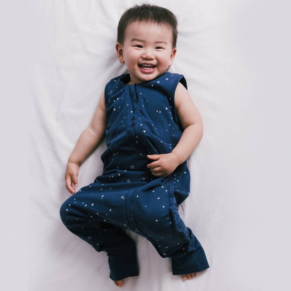 Child wearing a blue outfit with star pattern lying on a white surface