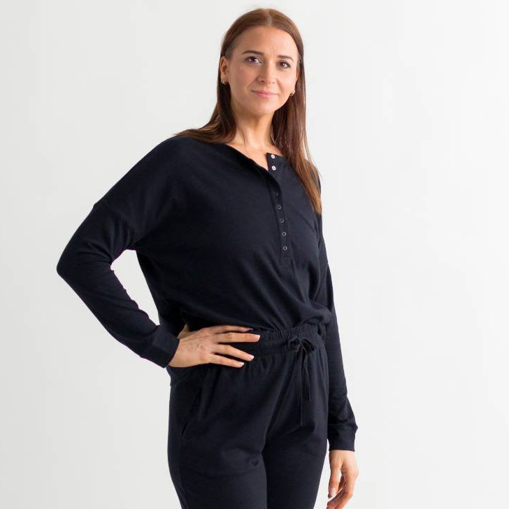 Woman wearing a black breastfeeding top and lounge pants with drawstring waist on a white background