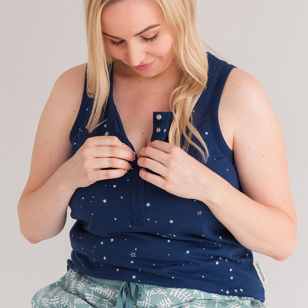 Woman wearing a navy blue sleeveless breastfeeding lounge PJ top with star patterns on a plain background