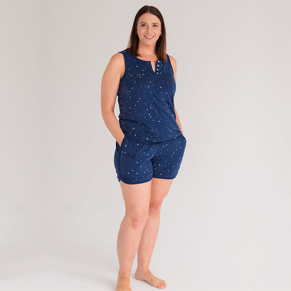 Woman wearing a navy blue pajama set with star pattern on a light gray background