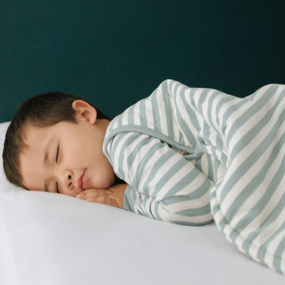 Child sleeping in a striped outfit with a dark blue background