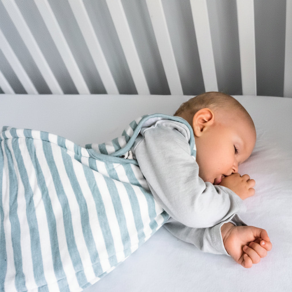 Baby sleeping in a crib with a striped winter sleeping bag