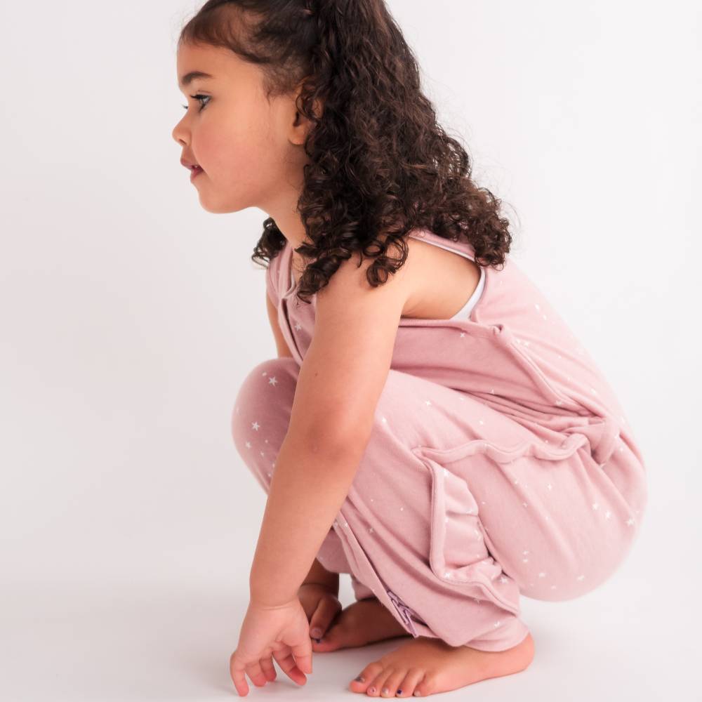 Child in pink merino kids onesie with white polka dots on a light background