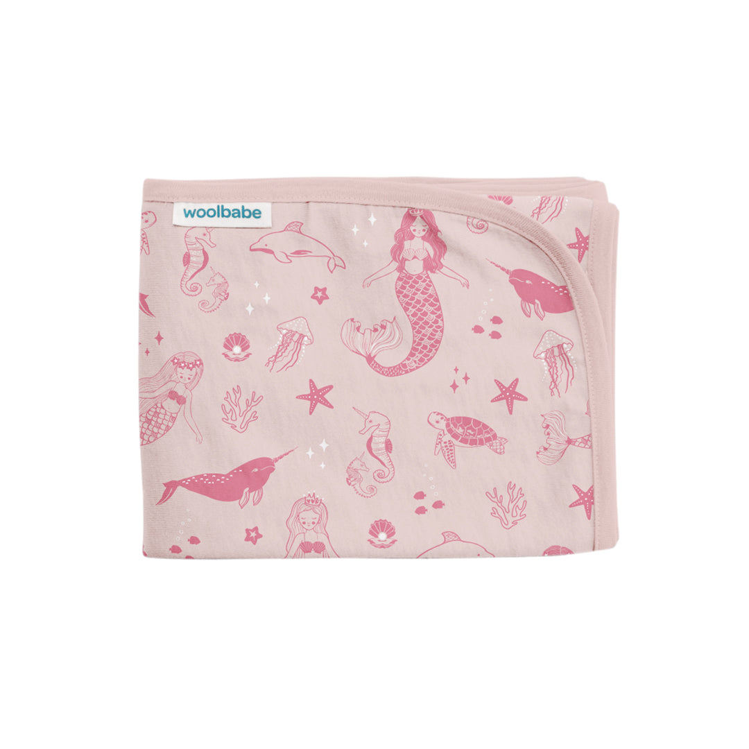 Pink baby blanket with mermaid and sea creature pattern on a white background