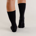 Black knee-high woolbabe socks worn by a person on a light gray background