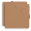 A stack of fitted sheet covers in a warm tan or camel color, showing the elasticized corner binding, set against a plain white background.