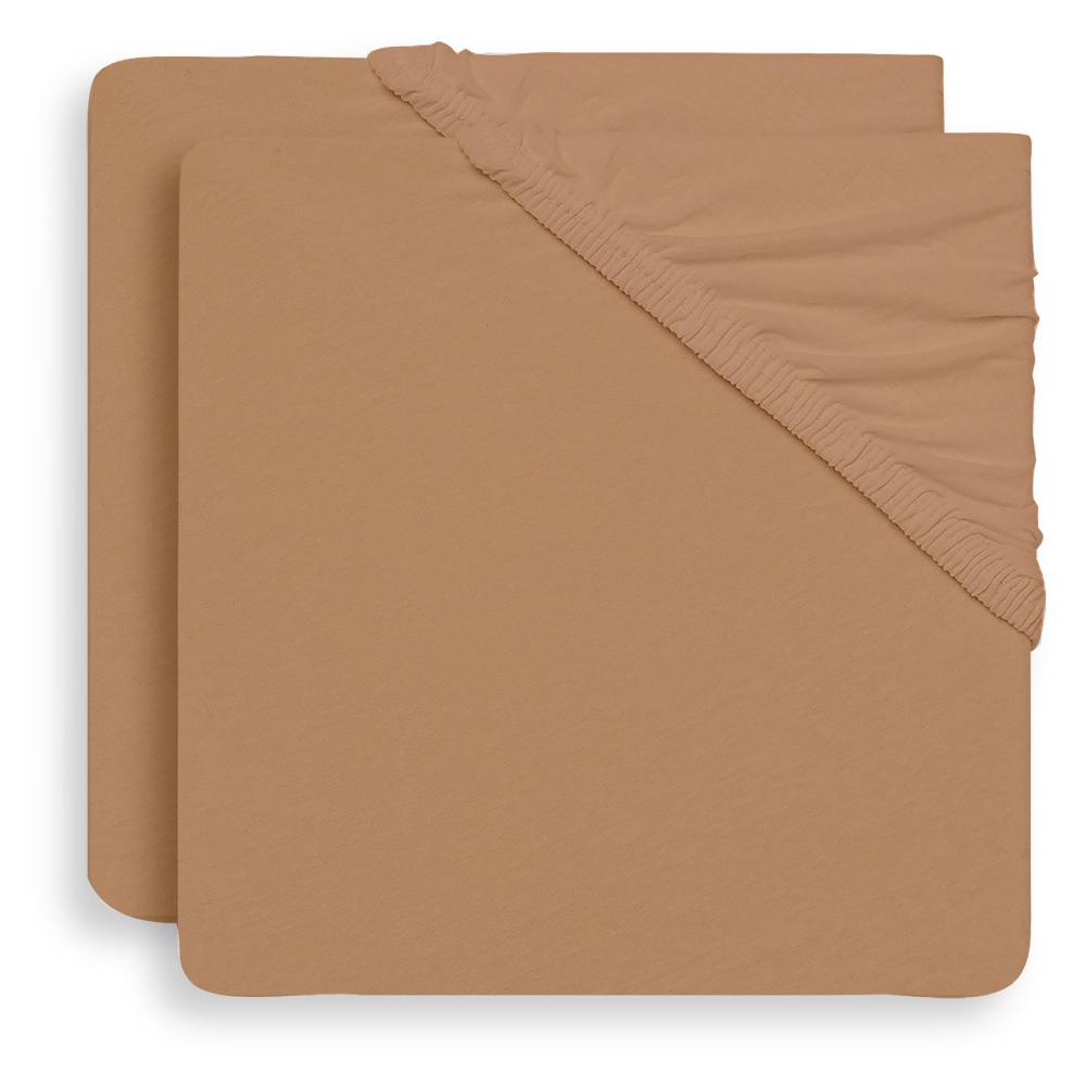 A stack of fitted sheet covers in a warm tan or camel color, showing the elasticized corner binding, set against a plain white background.