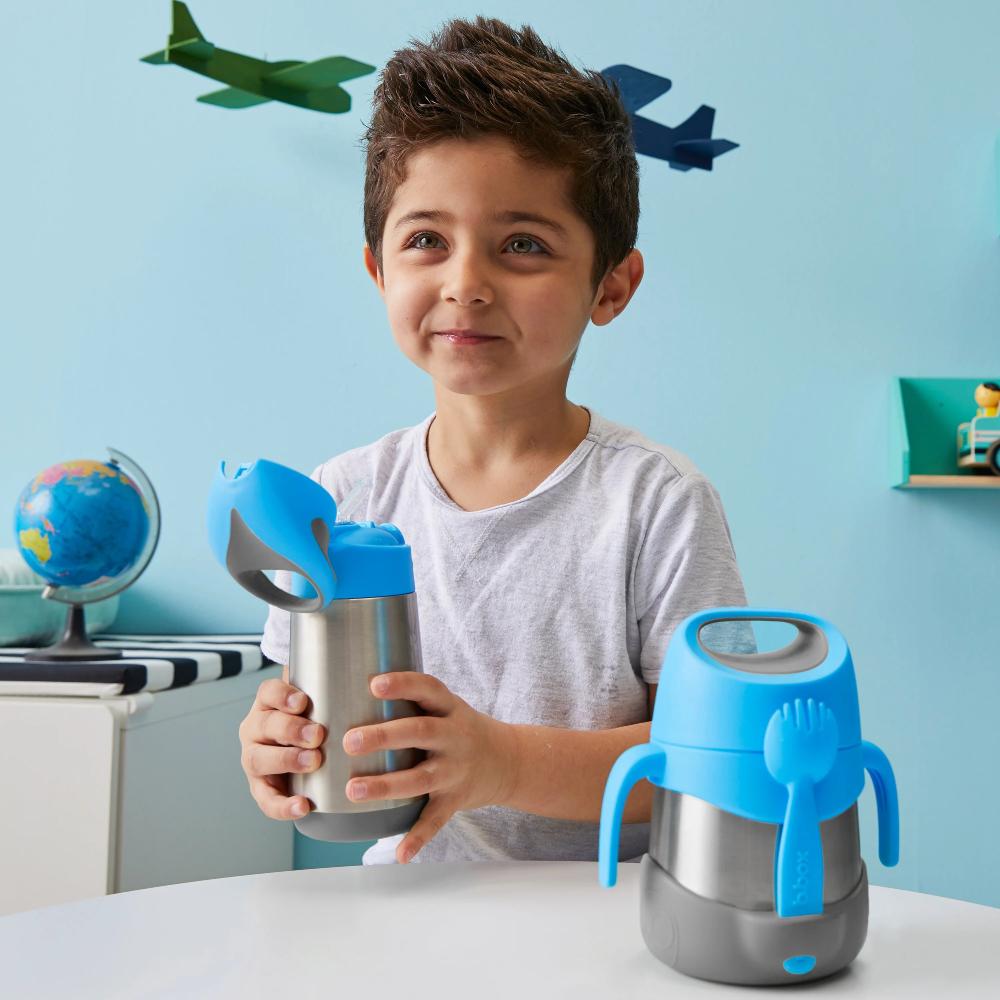 Child holding a blue and silver insulated food jar with airplane decorations on the wall.