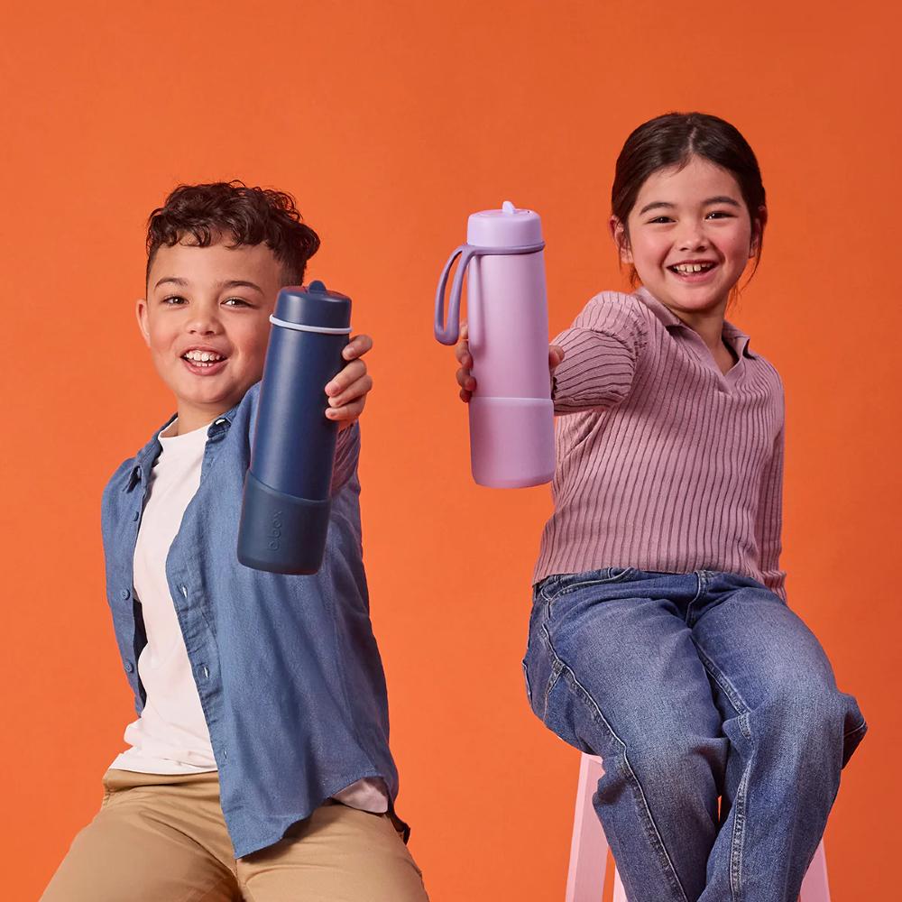 Two children holding water bottles against an orange background