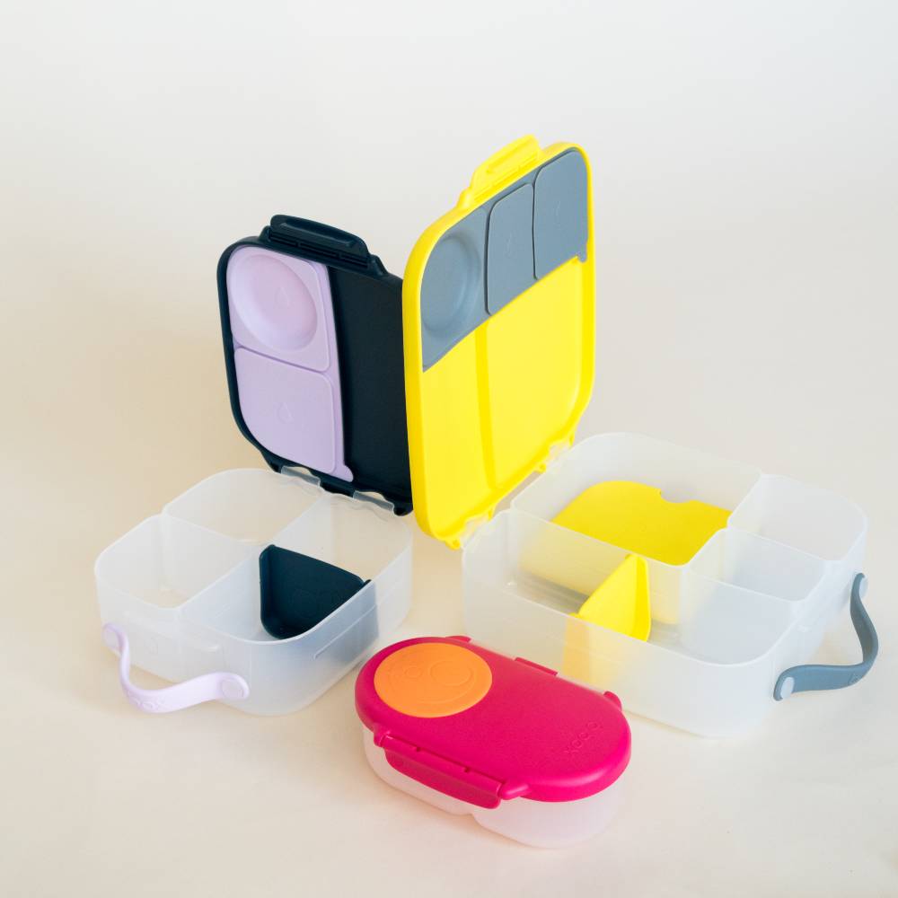 Colorful lunchbox, mini and snack containers with multiple compartments on a light beige background