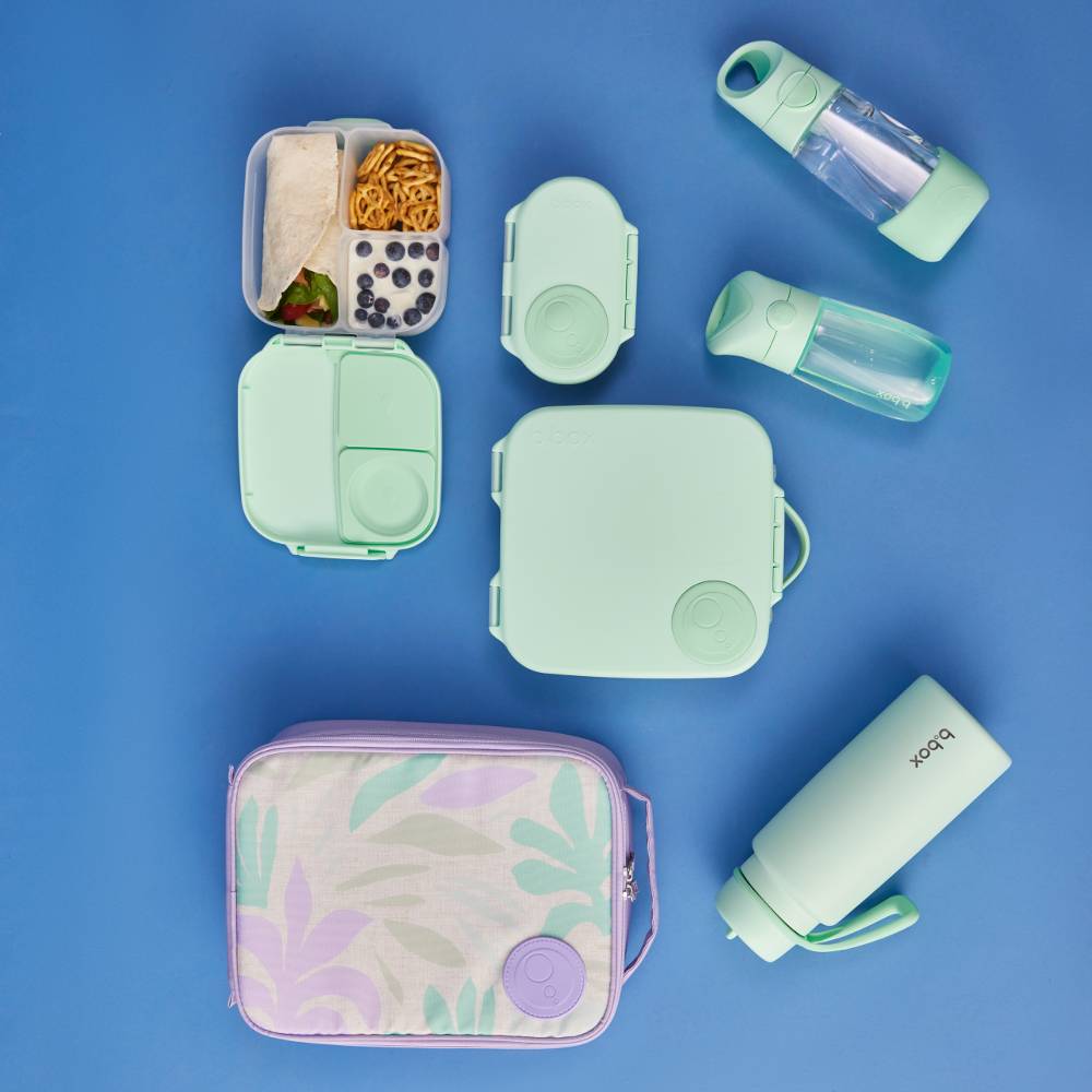 Collection of green and pastel lunch containers and bottles on a blue background
