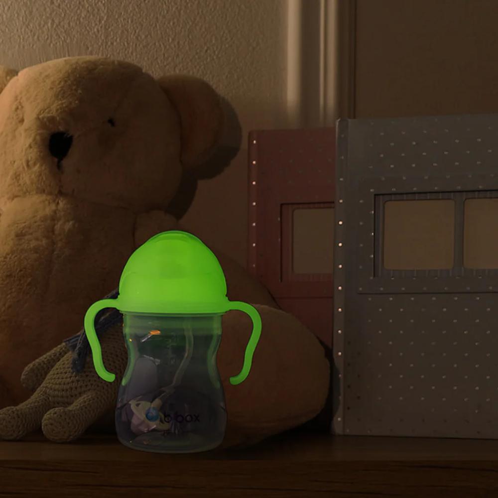 Glow in the Dark sippy cup with a teddy bear and books in a dimly lit room
