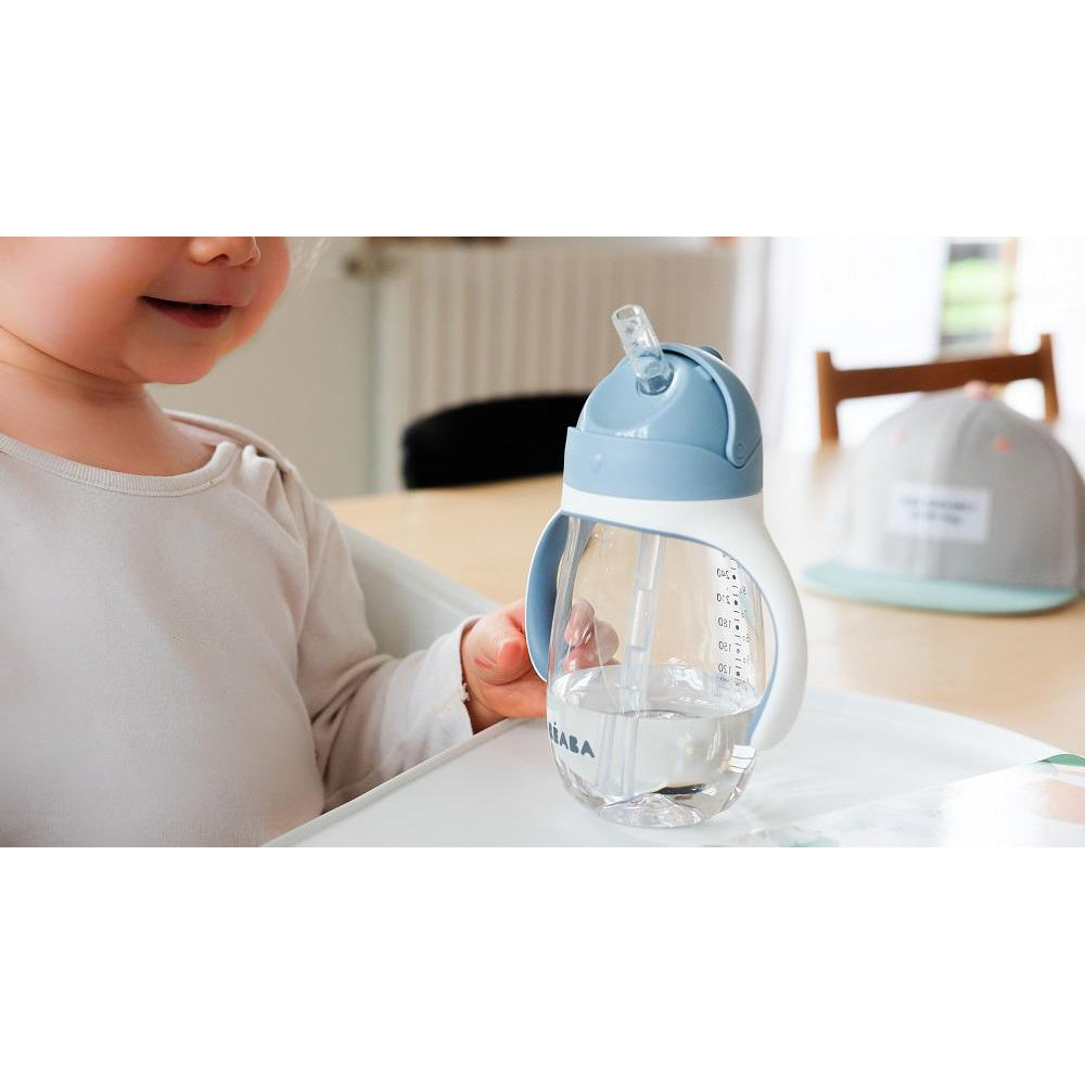 Child holding a blue and clear sippy cup indoors
