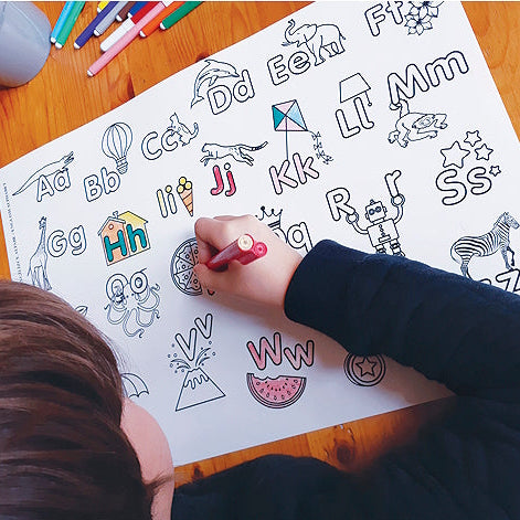 child colouring in english alphabet funny mat on a table with felt tips