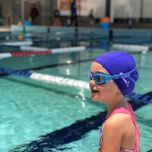 A child in the swimming pool wearing blue funkies googles. 