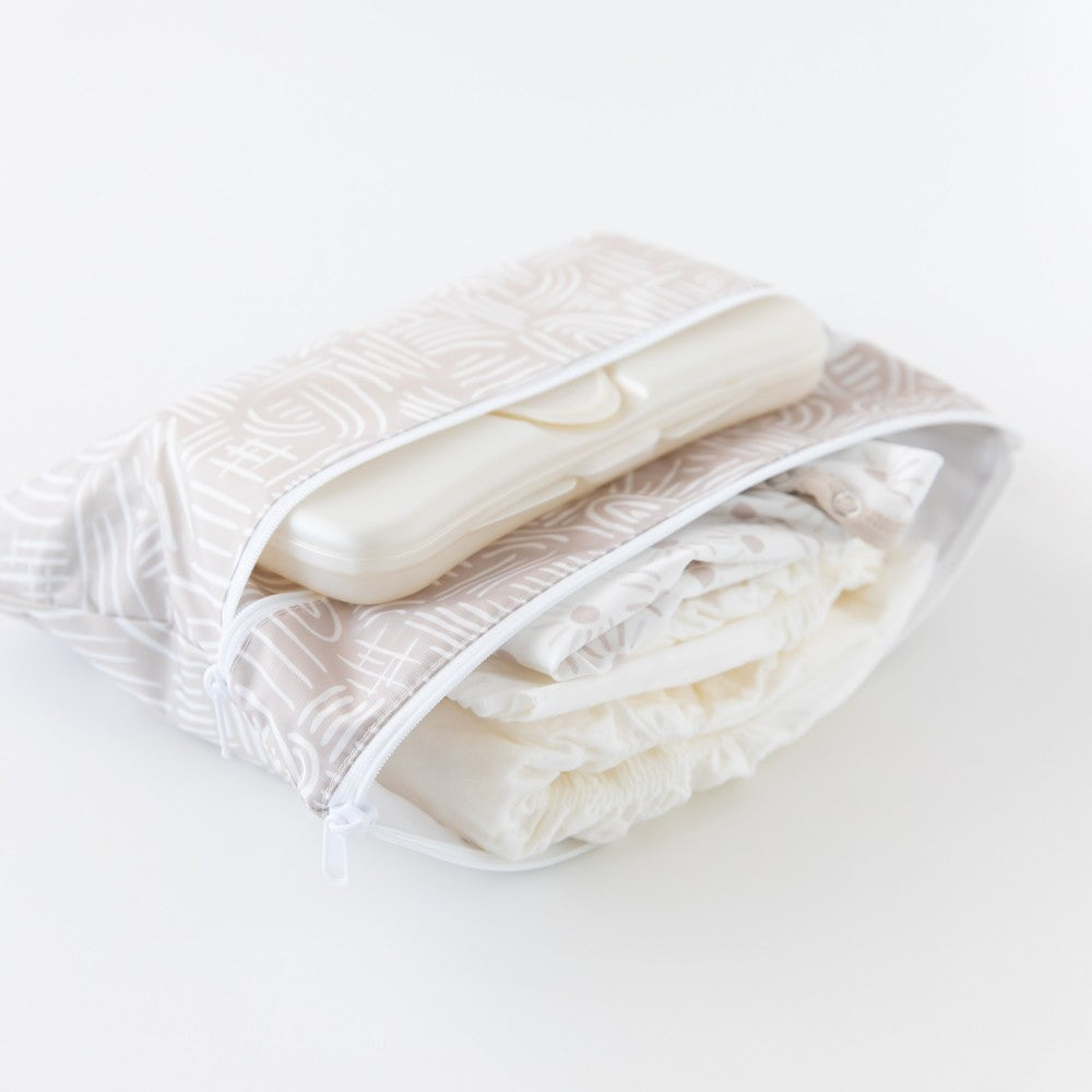 Nappies, clothing and wipes inside a wet and dry clutch with beige and white pattern on a white background 