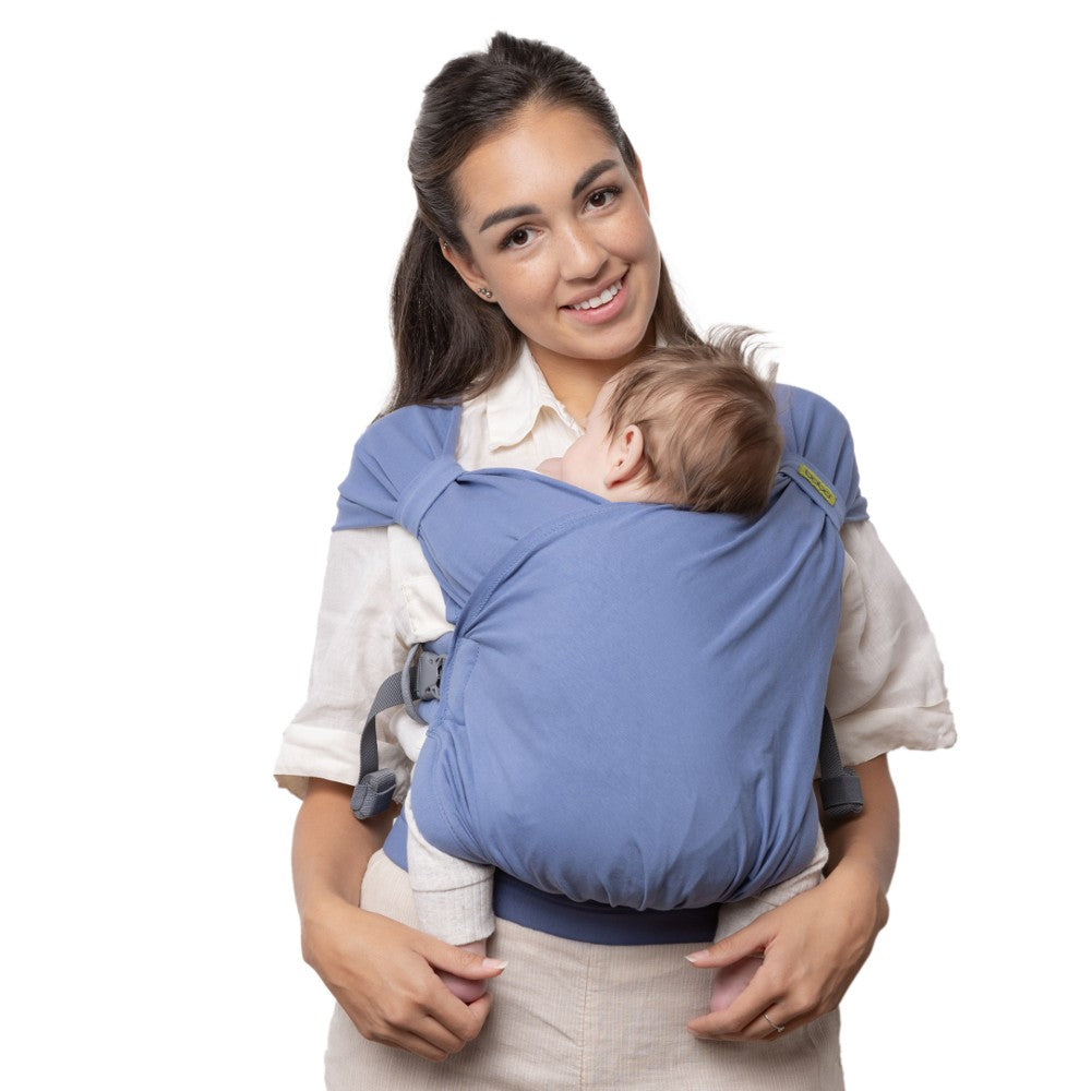 Woman holding a baby in a blue baby carrier against a white background