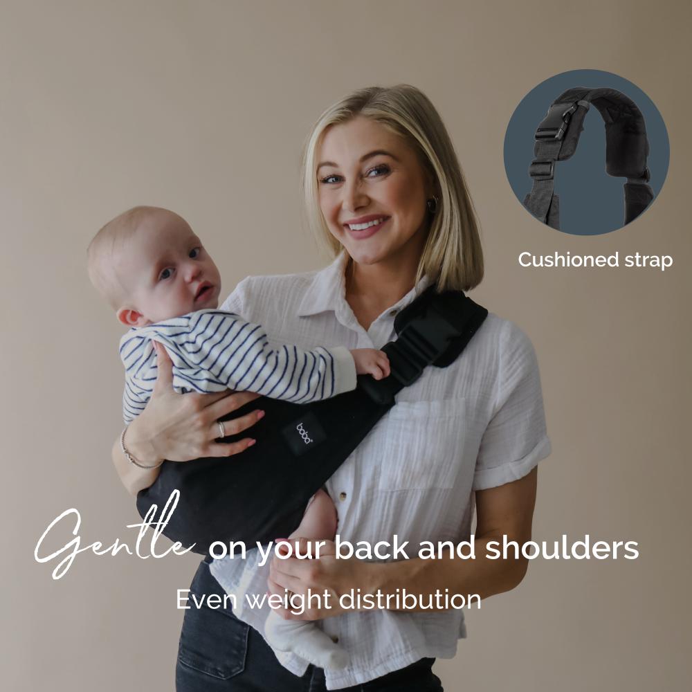 Woman holding a baby in a toddler sling carrier with text about cushioned strap and weight distribution.