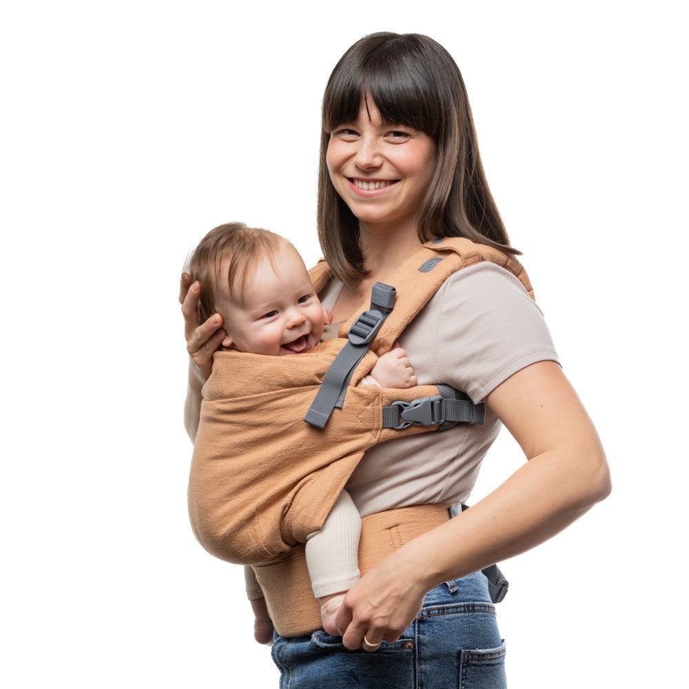 Woman holding a baby in a linen natural baby carrier from Boba against a white background
