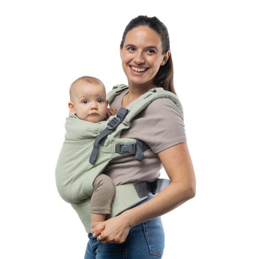 Woman carrying a baby in a green baby carrier on a white background