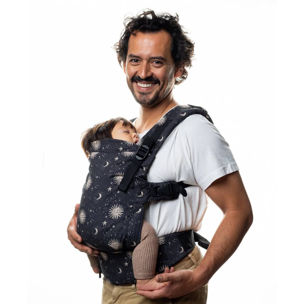 Man carrying a baby in a dark blue baby carrier with celestial pattern called Cosmos on a white background